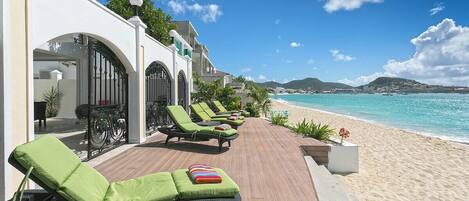 A beachside lounge area with sun loungers and a wooden deck overlooking the ocean.