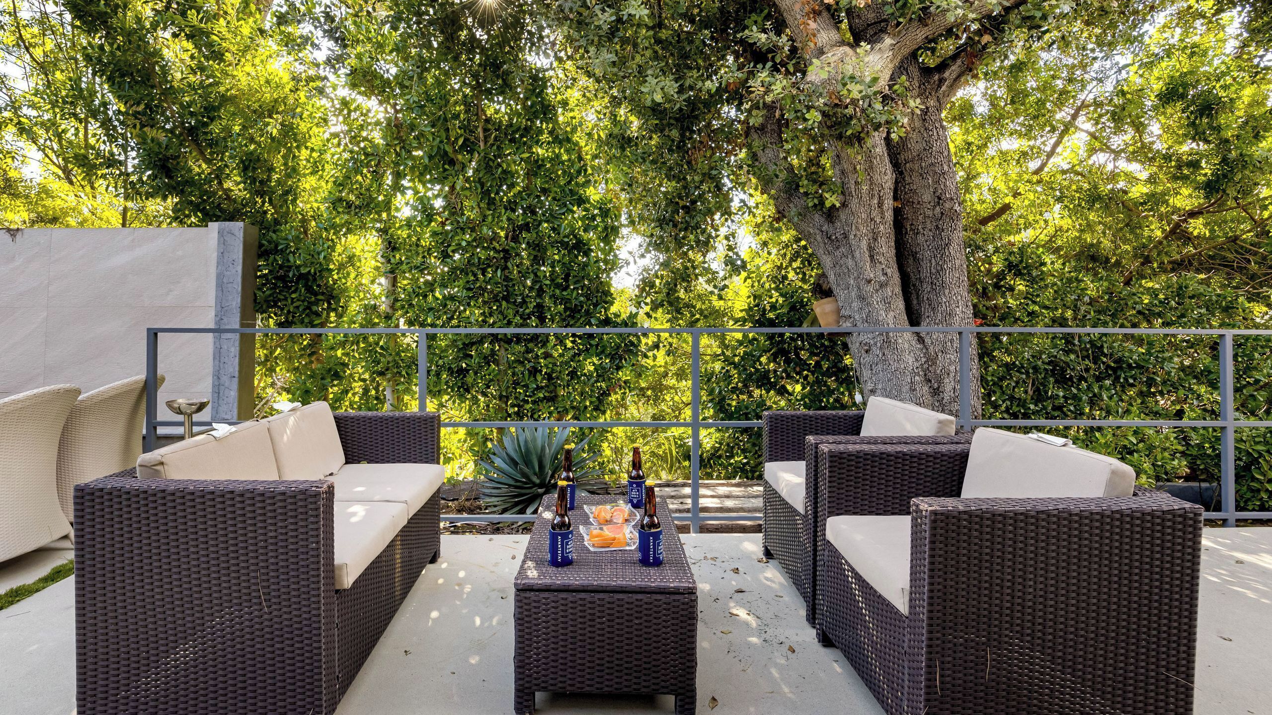 Un espacio al aire libre con mobiliario de mimbre y una mesa con botellas.