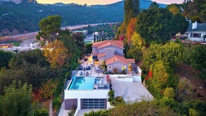 A modern two-story house with a swimming pool, surrounded by trees and a hilly landscape. - LA Hillside Retreat w/ Pool, Views, Fire Pit & Outdoor Lounging Casa Bellagio by Avantstay (Los Angeles)