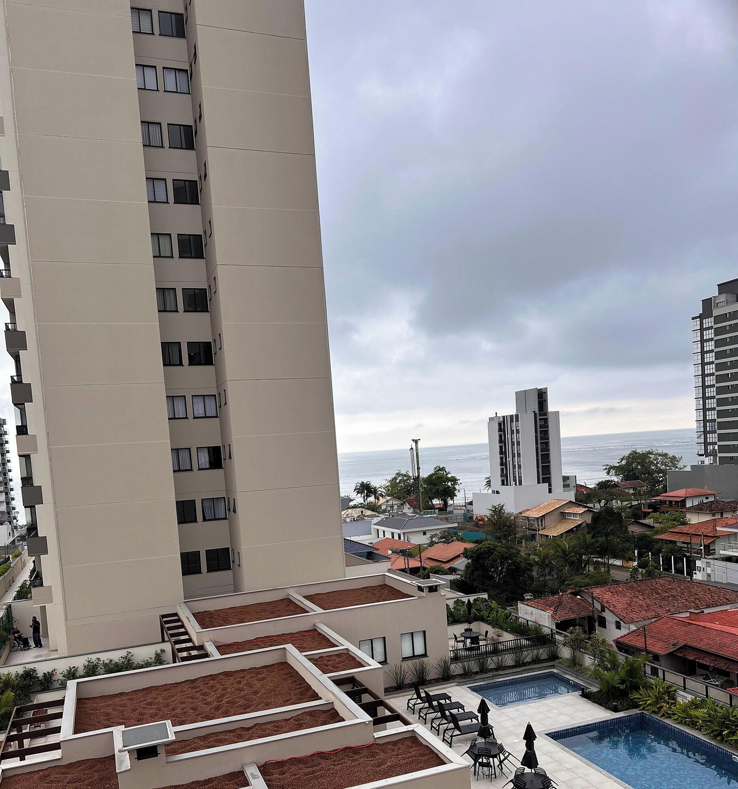 A high-rise building with a rooftop garden and a swimming pool.
