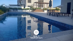 A swimming pool with tiled edges, surrounded by outdoor seating and a pergola. - Skyline Confort Club - Blue Horizon (Penha)
