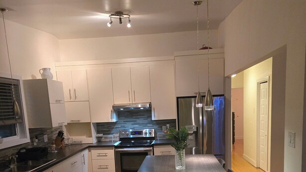 A modern kitchen with white cabinets, stainless steel appliances, and a central island. - Nature view retreat (Gatineau)
