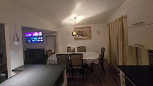 A dining area with a table, chairs, a chandelier, and a television displaying a menu. - Nature view retreat (Gatineau)