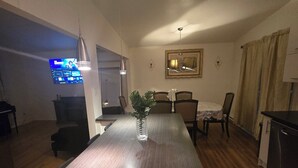 A modern kitchen with a central island, wooden flooring, and a dining area with chairs and a table. - Nature view retreat (Gatineau)