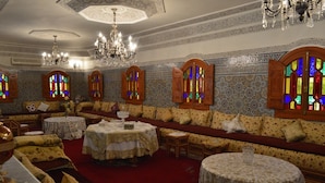 A room with patterned walls, a red carpet, and multiple round tables with white tablecloths. - Villa Moulay Bousselham (Marrakech)