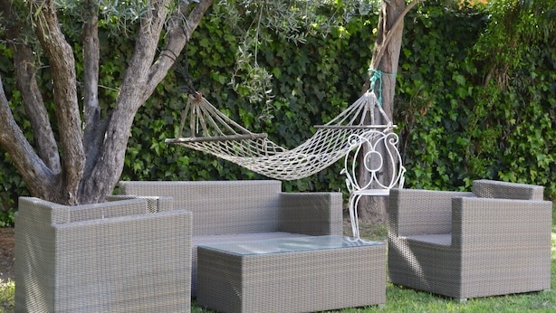 A wicker outdoor seating area with a hammock, surrounded by greenery. - Villa Moulay Bousselham (Marrakech)