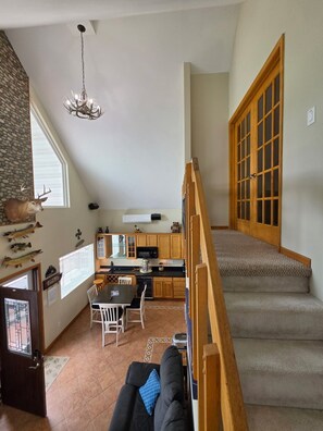 Ein großzügiger Wohnbereich mit einer Treppe zu einem Schlafzimmer auf dem Dachboden, eine Küche mit modernen Geräten und ein Essbereich.
