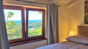 Ein Schlafzimmer mit einem Bett, einem Fenster mit Vorhängen, einer Lampe und einem Bild an der Wand.