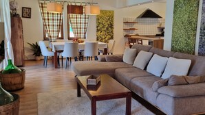 Ein modernes Wohnzimmer mit einer großen Eckcouch, einem Holztisch und einem Essbereich mit Tisch und Stühlen.