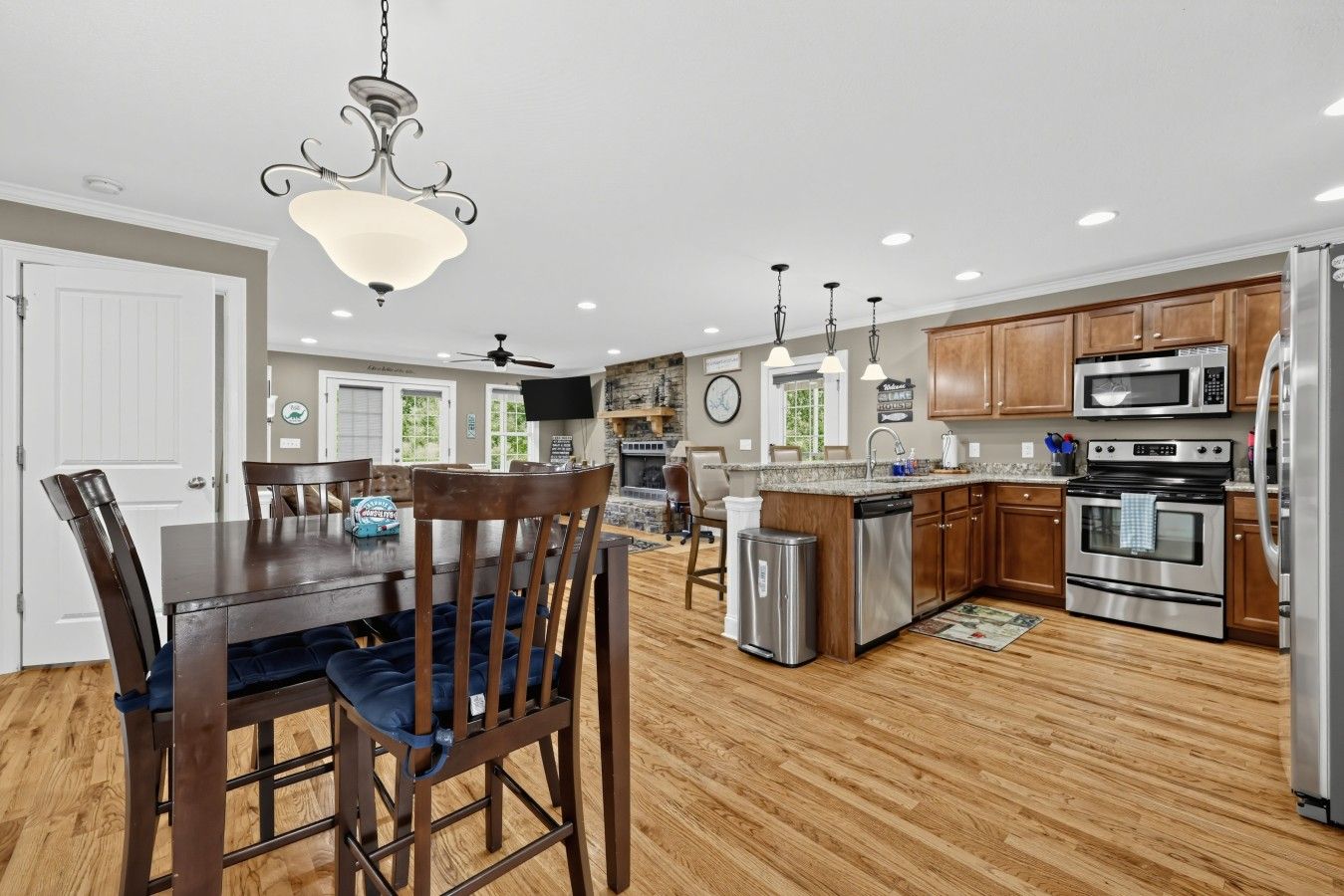 A modern kitchen with wooden cabinets, stainless steel appliances, and a dining area with a wooden table and chairs.