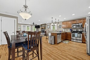 Eine moderne Küche mit Holzschränken, Edelstahlgeräten und einem Essbereich mit Holztisch und Stühlen.