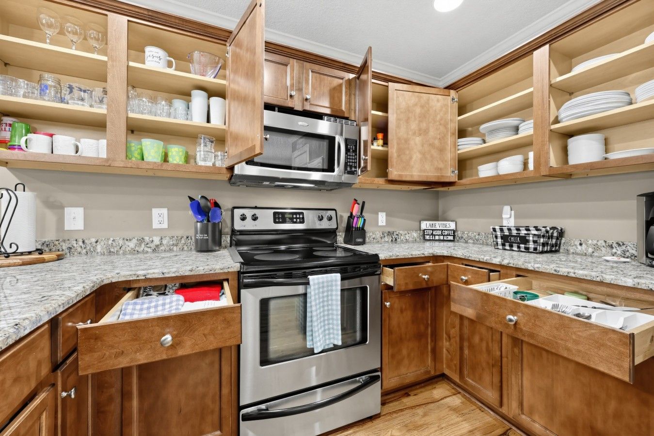 Una cucina con mobili in legno, un fornello in acciaio inossidabile e un forno a microonde.