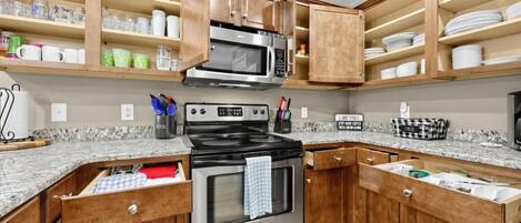 Una cucina con mobili in legno, un fornello in acciaio inossidabile e un forno a microonde.