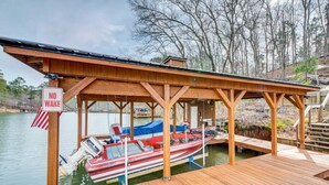 A wooden dock with a covered seating area and a boat docked at the end.