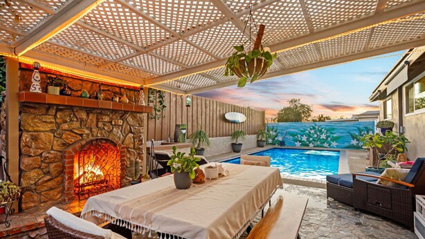 An outdoor patio with a stone fireplace, a pool, and outdoor seating. - Casa Malta Spa and Pool (San Diego)