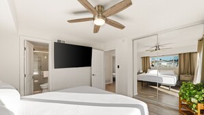 A modern hotel room with a large bed, a ceiling fan, a flat-screen TV, and a view of the outside through a sliding door. - Casa Malta Spa and Pool (San Diego)