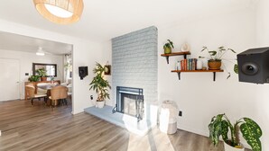 A modern living room with a fireplace, wooden flooring, and a dining area with a table and chairs. - Casa Malta Spa and Pool (San Diego)