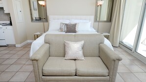 A hotel room with a bed, a sofa, a small table, and a mirror. - Gulf Front 8th Floor Studio - Sleeps up to 4 (Panama City Beach)