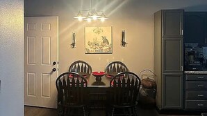 A dining area with a table and four chairs, a chandelier, a door, and a cabinet. - This house will meet all your needs (Harrison)