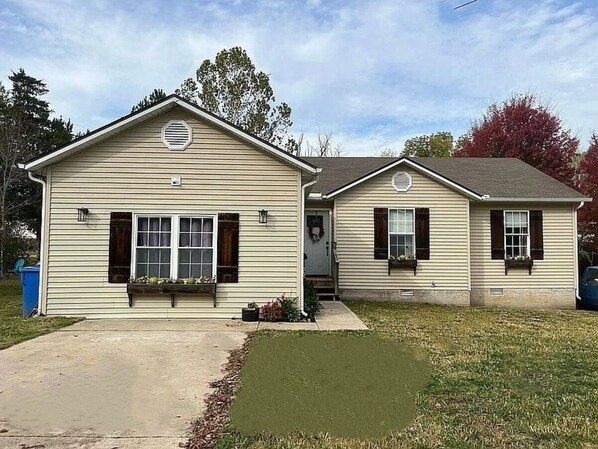 Une maison à deux étages avec un porche à l’avant, un garage et un petit jardin devant.