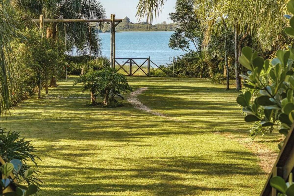 Un jardin bien entretenu, avec un chemin dégagé menant à une balançoire en bois, le tout surplombant une étendue d’eau.