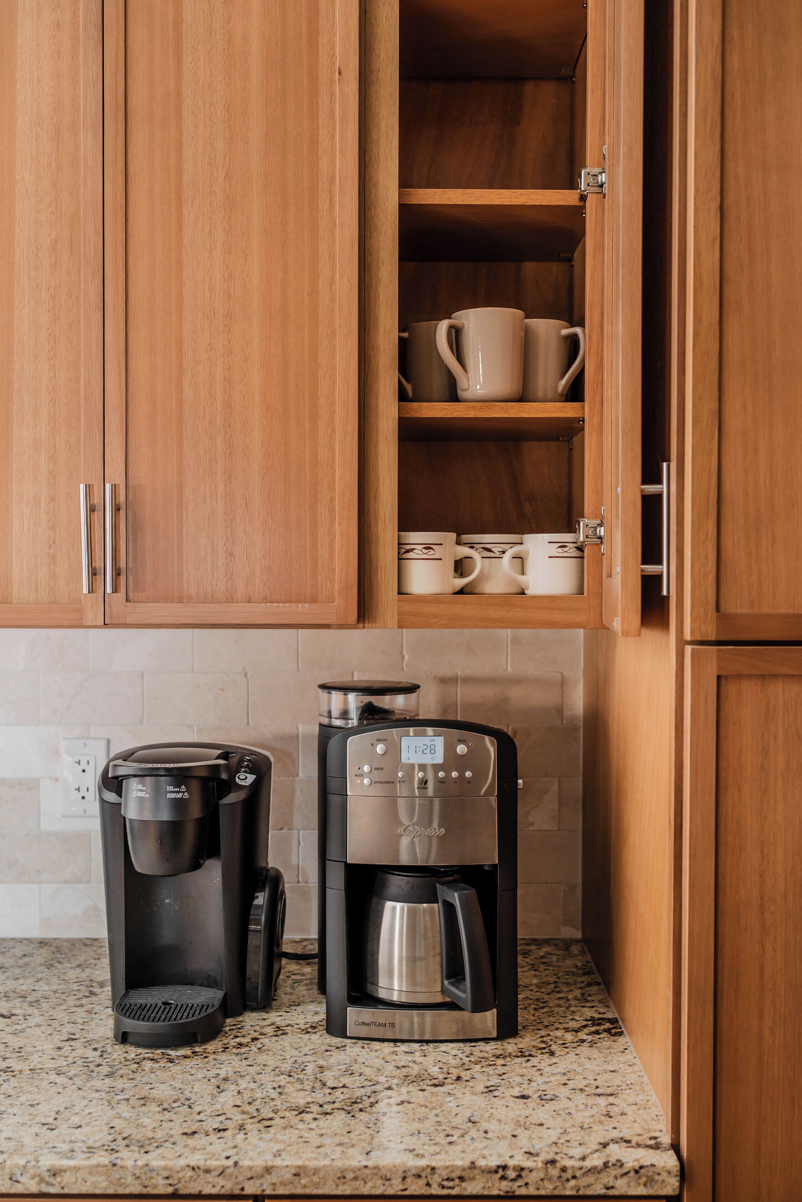 Een keuken met houten kastjes, een koffiezetapparaat en een koffiekan.