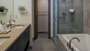 Een moderne badkamer met een douchecabine van glas, een ruime badkuip en een wastafel met dubbele wasbakken en een spiegel.