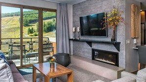 Een moderne woonkamer met een open haard, een flatscreen televisie en een balkon met een schitterend uitzicht.