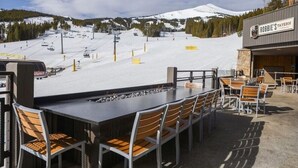 Een terras met zitplaatsen en uitzicht op een piste en een berg op de achtergrond.