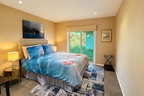 A bedroom with a bed, a nightstand, a lamp, a window with a view of greenery, and a painting on the wall. - Mid-Century Escape. Hot Tub. Lush Garden. A/C. Bar (Ojai)