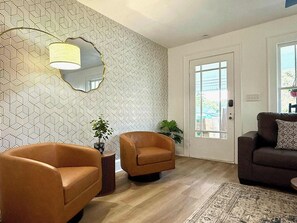 A living room with two armchairs, a sofa, a patterned wall, and a door leading outside. - 3 King Beds -Fast WiFi, Fenced Yard & Pet Friendly (Lakeland)