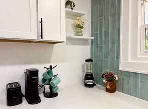 A kitchen with white cabinets, a coffee maker, a blender, and a mug rack. - 3 King Beds -Fast WiFi, Fenced Yard & Pet Friendly (Lakeland)
