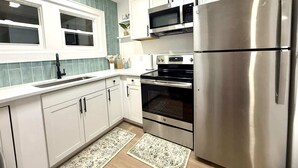 Eine moderne Küche mit weißen Schränken, Edelstahlgeräten, einem Doppelbackofen und einem Kühlschrank.