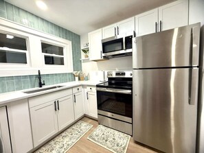 A modern kitchen with white cabinets, stainless steel appliances, a double oven, and a refrigerator. - 3 King Beds -Fast WiFi, Fenced Yard & Pet Friendly (Lakeland)