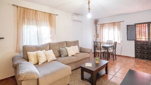 Una sala de estar con sofá, mesa de centro y comedor con sillas y mesa.