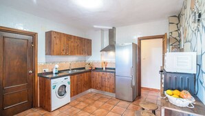 Cocina compacta con armarios de madera, lavadora, refrigerador y microondas.