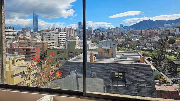 A cityscape with a prominent skyscraper, a variety of building styles, and a mountainous backdrop. - Apartment in unbeatable location, spectacular view (Providencia)