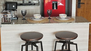 A compact kitchen with a red coffee machine, a microwave, and a toaster. There are two stools at the counter. - Apartment in unbeatable location, spectacular view (Providencia)