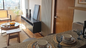A modern kitchen with a dining area, featuring a wooden table, a black cabinet, and a view of the city through large windows. - Apartment in unbeatable location, spectacular view (Providencia)