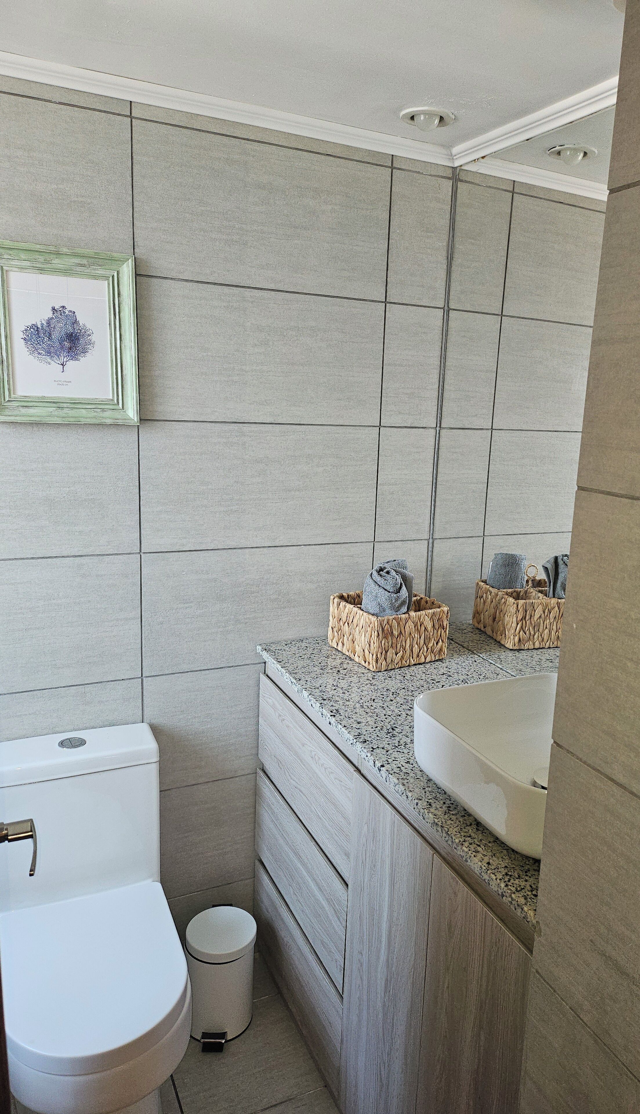 A modern bathroom with a toilet, sink, and a framed picture on the wall.