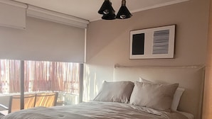 A bedroom with a large bed, a ceiling light fixture, and a window with blinds. - Apartment in unbeatable location, spectacular view (Providencia)