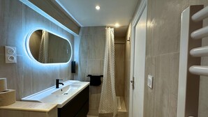 Un baño moderno con un espejo grande, lavamanos dobles y zona de ducha.
