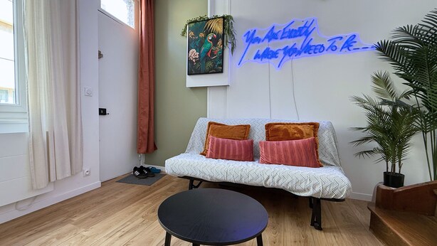 Una sala de estar moderna con un sofá, una mesa redonda y un letrero de neón en la pared.