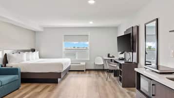Une chambre d’hôtel équipée d’un lit, d’un bureau, d’une chaise, d’une télévision et offrant une vue sur l’extérieur.