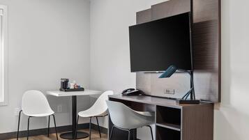 Un espace de bureau moderne comprenant un bureau, deux chaises, un téléviseur à écran plat et une lampe de bureau.