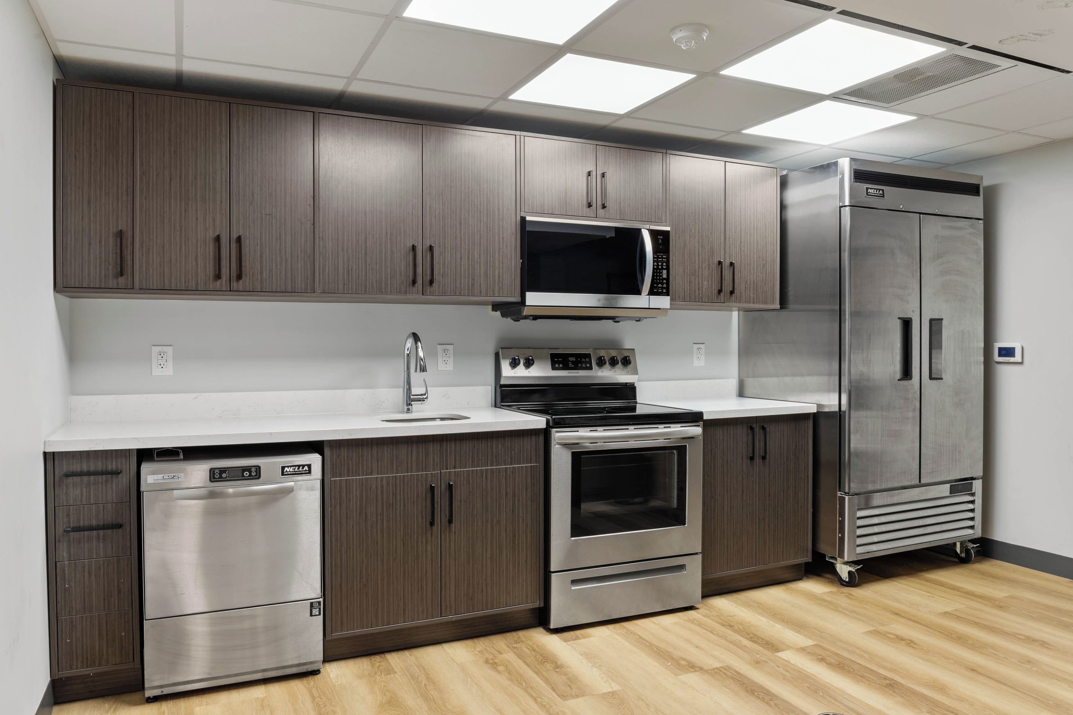 A modern kitchen with stainless steel appliances, wooden cabinets, and a white countertop.