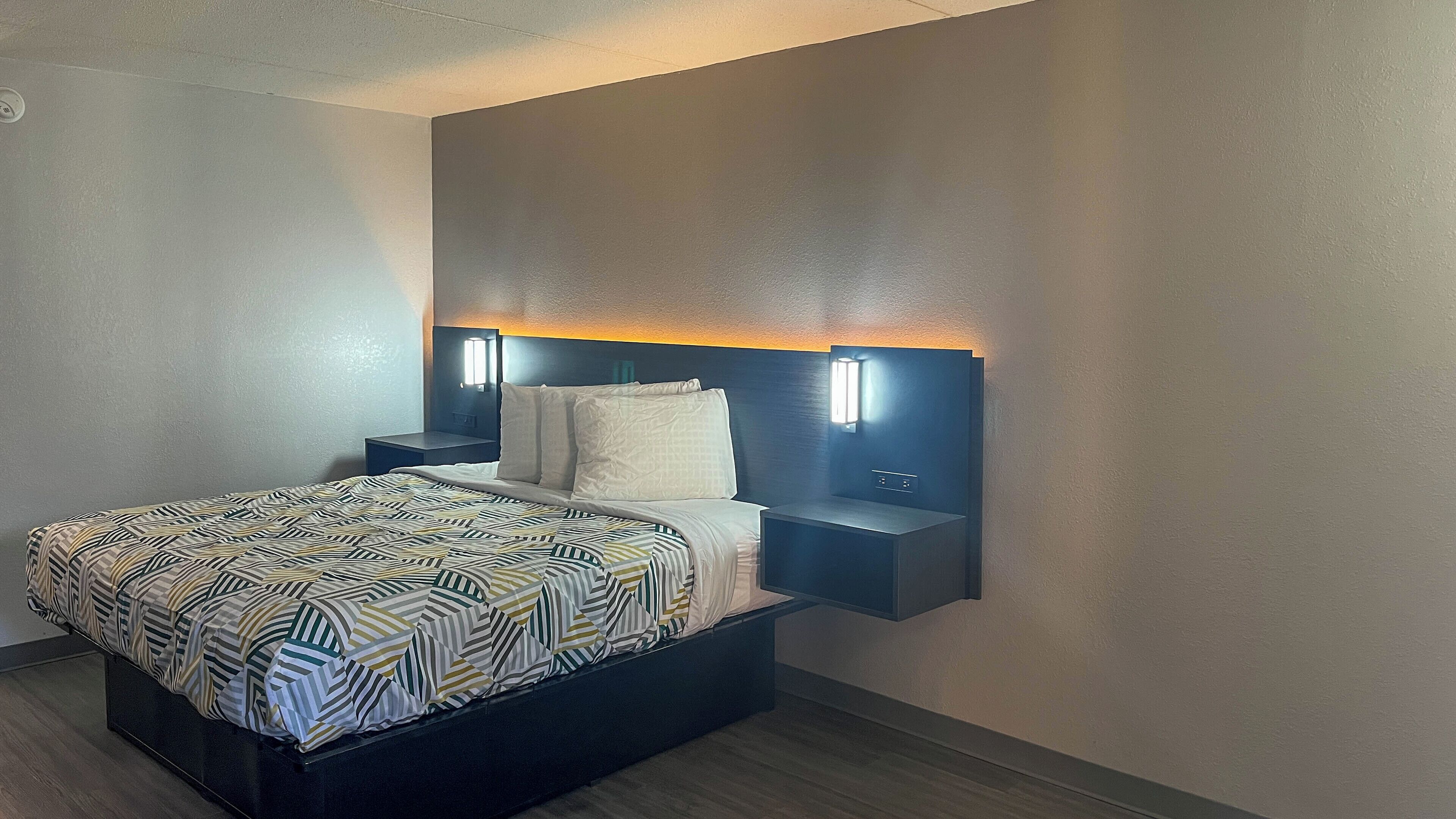 Une chambre d’hôtel moderne, équipée d’un lit, de tables de chevet et d’appliques murales.