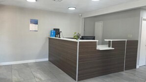 Un'area di accoglienza con una scrivania in legno scuro, una TV a schermo piatto e una piccola pianta.