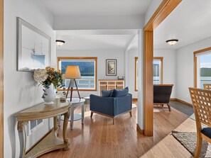A spacious living area with a view of a lake, a blue sofa, a wooden table with a lamp, and a fireplace. - Waterfront private cabin just 5 miles from downtown Ketchikan (Ketchikan)