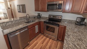 A kitchen with wooden cabinets, a stainless steel oven, a microwave, a dishwasher, and granite countertops. - Cozy 1-bedroom condo seconds from bus line in East Vail, perfect for getaways. (Vail)